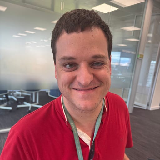 Oriol Gómez Sentís, sonriendo, con polo rojo y cordón de identificación